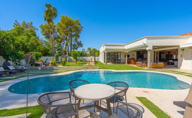 Backyard with pool, lounge chairs, and patio overlooking suburban neighborhood at sunset